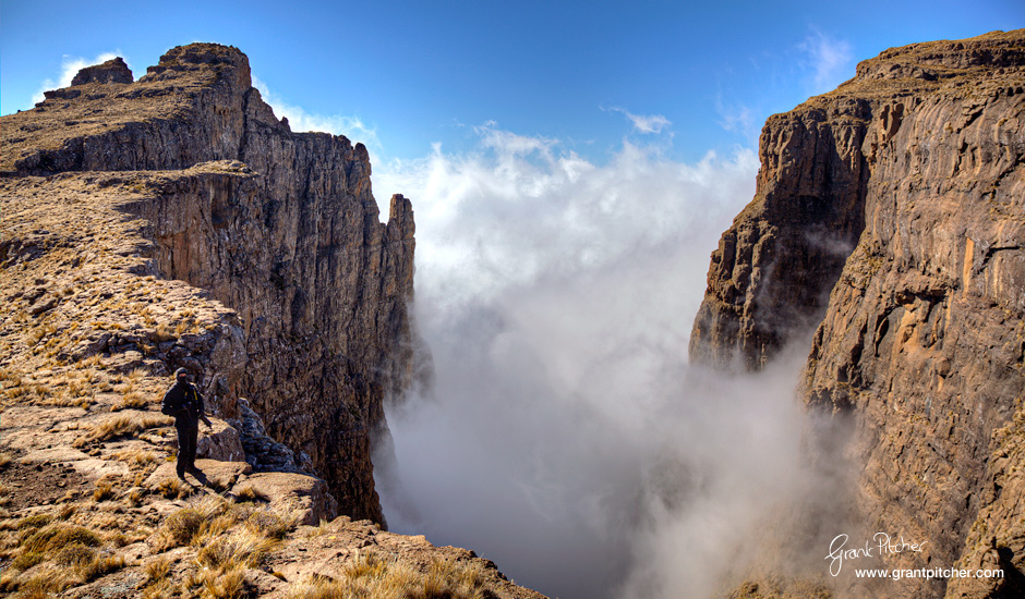 Capture the drama of the cloud as it billows in between the cutbacks. Hiker dwarfed in the scene.